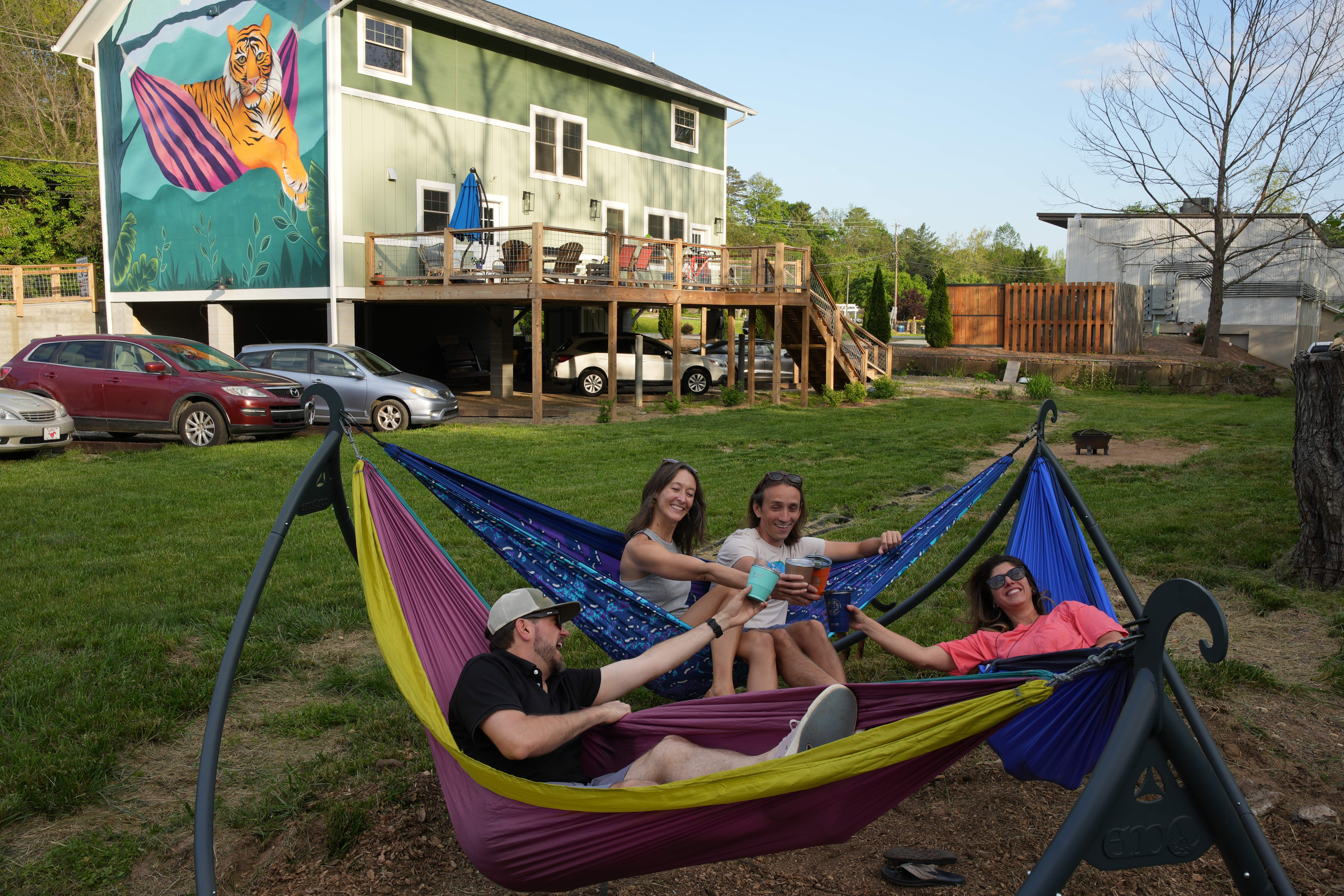 Guests enjoying ENO hammocks in the backyard with the Lazy Tiger mural in the background