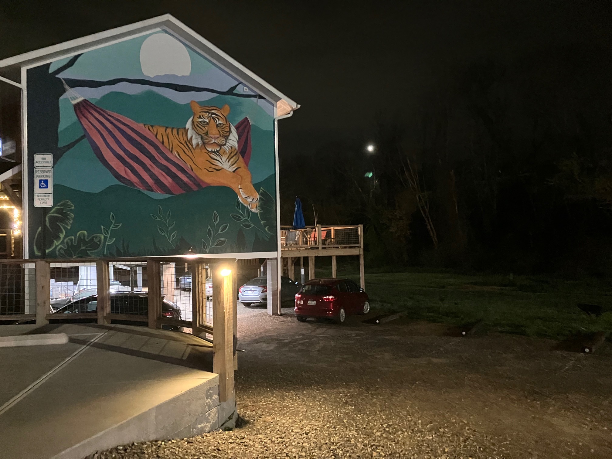 The Lazy Tiger Hostel parking lot at night, showing the mural and new lighting
